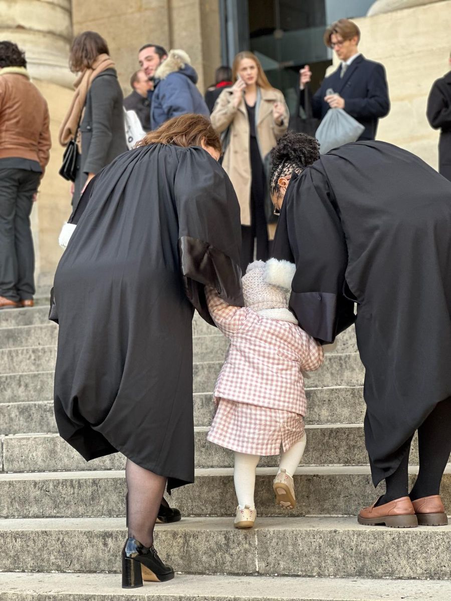Deux avocates en robe gravissant les marches du Palais en tenant la main d'une petite fille