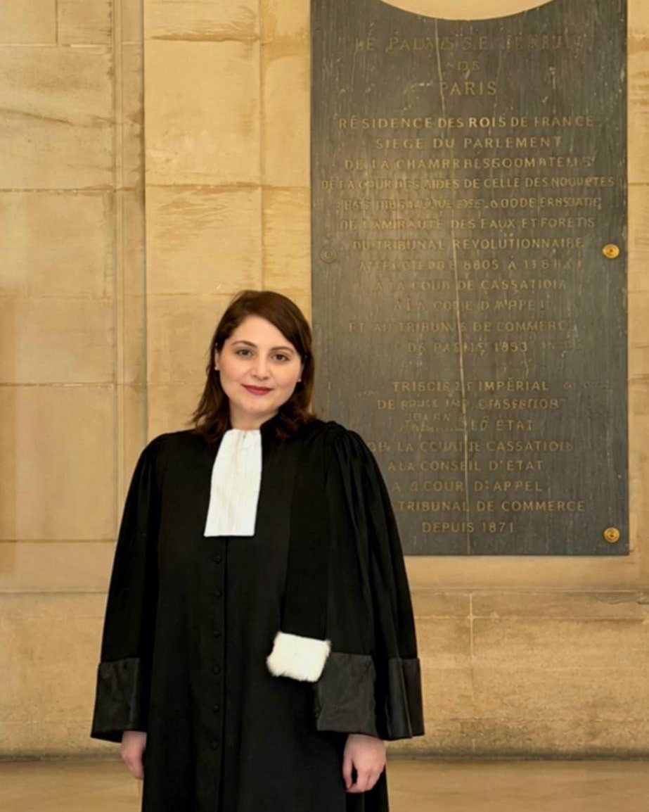 Maître Essra Siam en robe, devant la plaque du Palais de justice de Paris